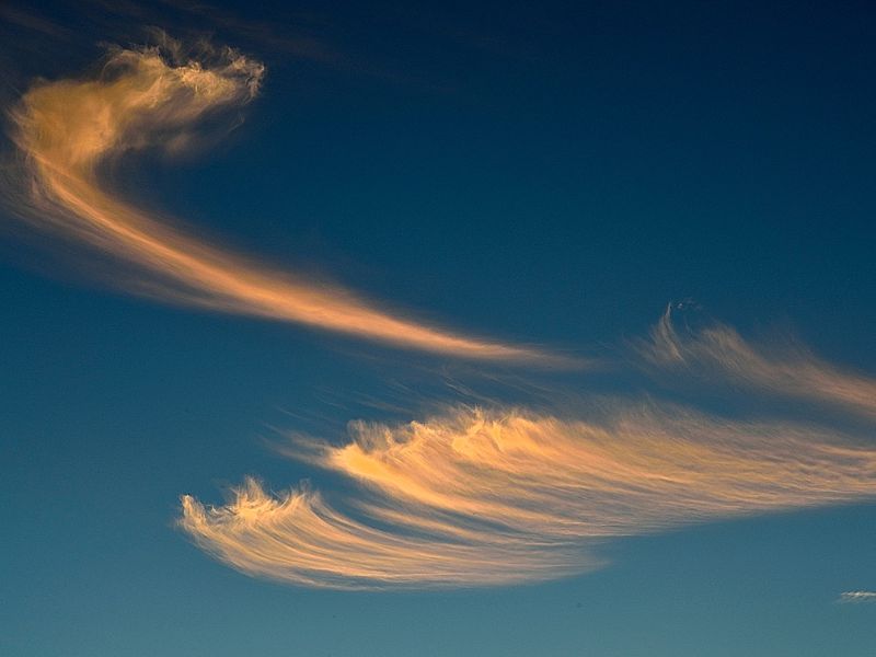 Zarte, goldene Wolken an einem tiefblauen Himmel, die wie ein sanfter Atemzug fließen, als Sinnbild für einen bewussten Stressabbau in Paderborn.